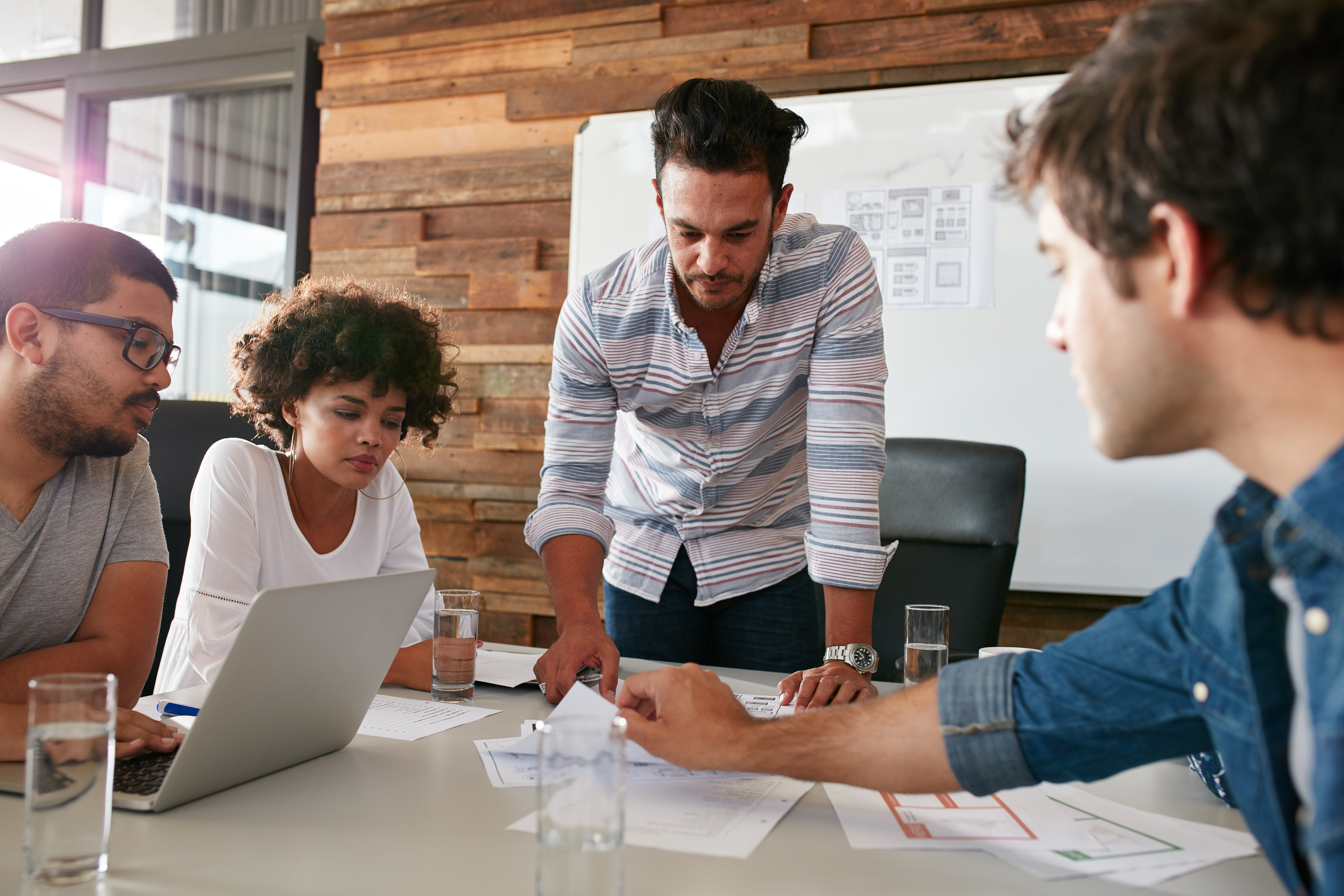 A team of 4 people working around a table in an office.